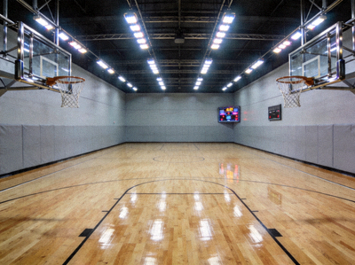 现代化室内篮球场馆实拍 - 整洁的木地板、明亮的灯光与标准篮筐